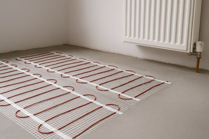 Elektrische vloerverwarming met verwarmingsmatten geïnstalleerd op een betonnen vloer voor gelijkmatige warmteverdeling Elektrische vloerverwarming met verwarmingsmatten geïnstalleerd op een betonnen vloer voor gelijkmatige warmteverdeling