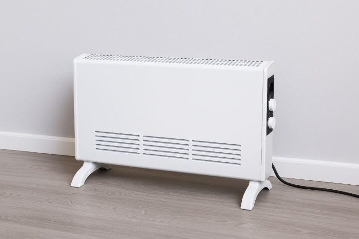 Slanke witte elektrische convectorheater op laminaatvloer, ideaal voor compacte ruimtes en energiezuinige verwarming. Slanke witte elektrische convectorheater op laminaatvloer, ideaal voor compacte ruimtes en energiezuinige verwarming.
